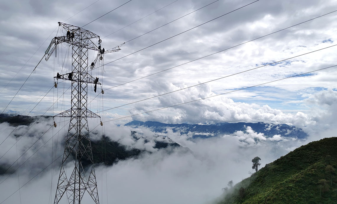 Cima de una montaña, cielo nublado y torre de energía.