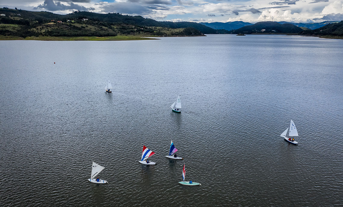 Sailboats on lake surrounded by mountains.