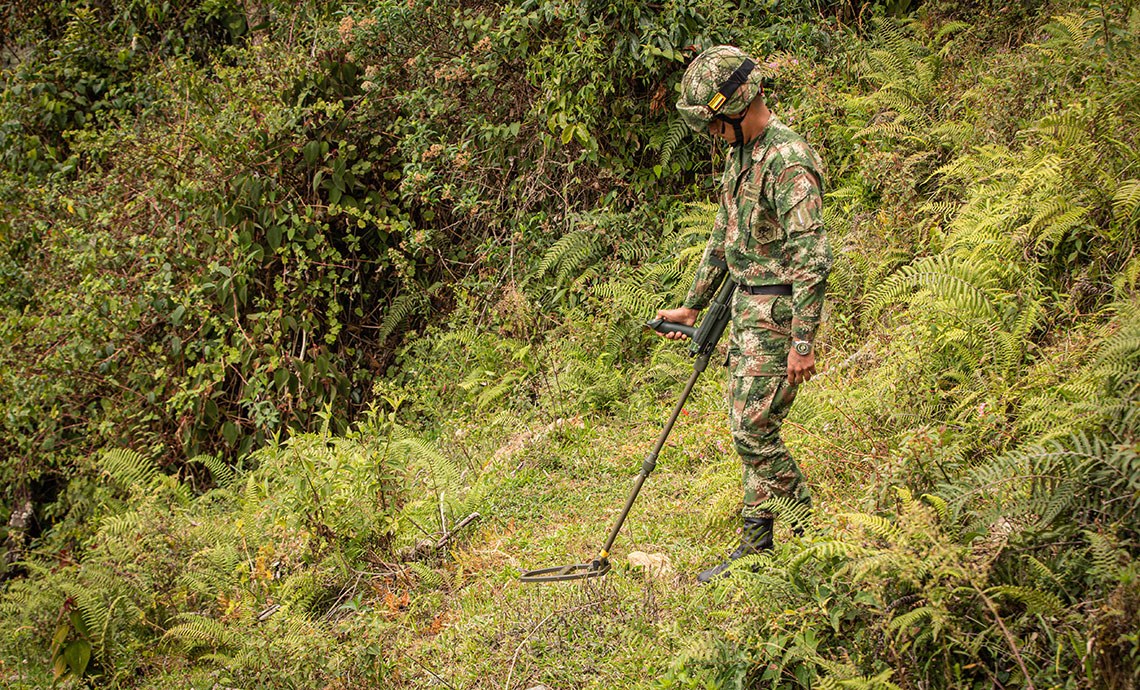 Un soldado está buscando minas antipersona para retirarlas.