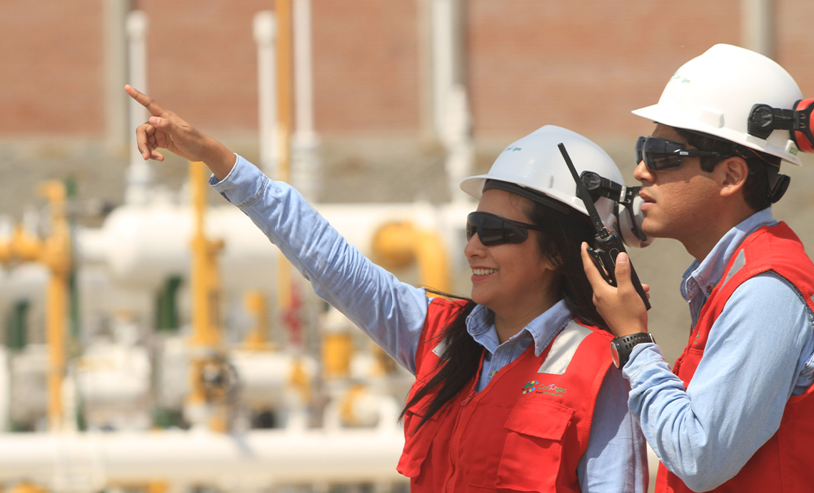 A worker speaks by radio and a female worker smiles and points afar.