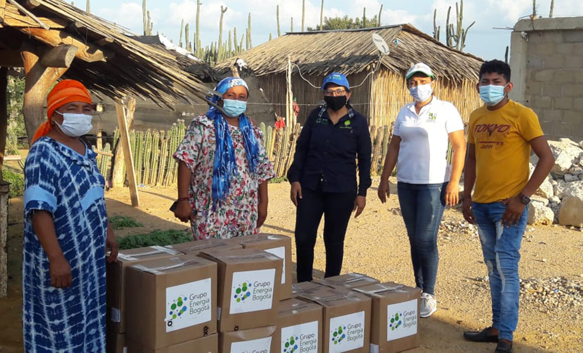 dos mujeres y un joven de la comunidad wayú reciben cajas con ayudas humanitarias de GEB.