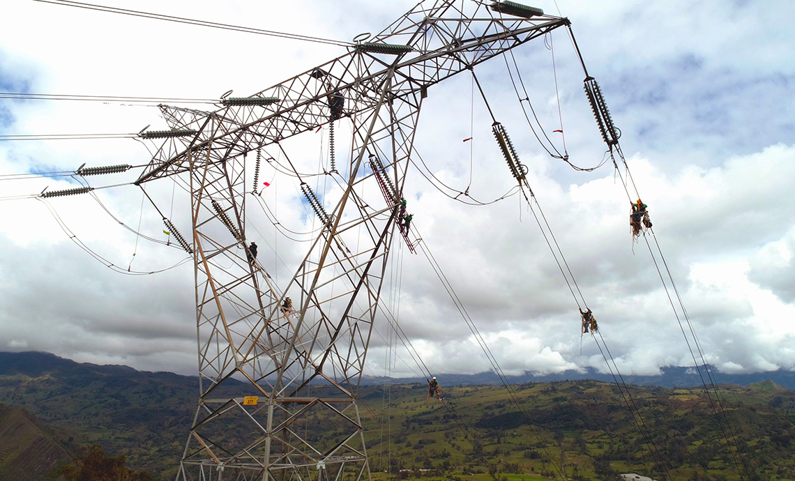 operarios realizan trabajo en altura sobre el cableado de una torre de energía.